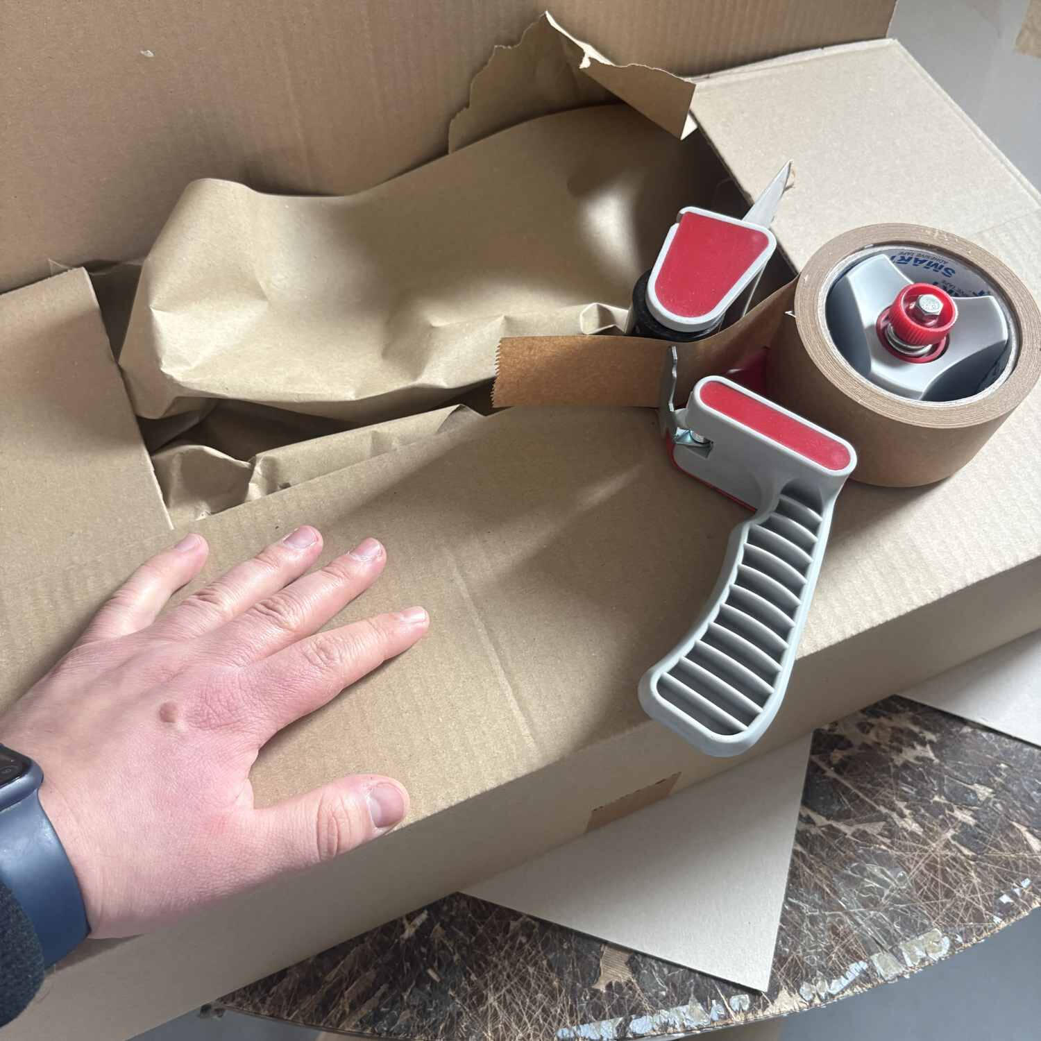Verpackung und Versandvorbereitung von Produkten mit Karton, Packmaterial und vorbereiteten Arbeitsschritten